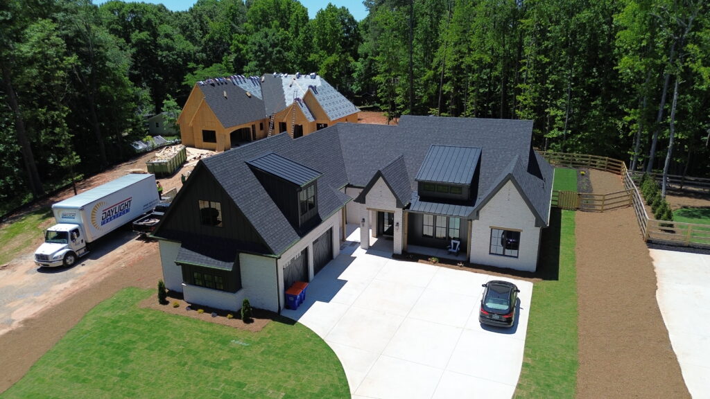 Aerial view of a large new construction home with a new dark architectural shingle roof