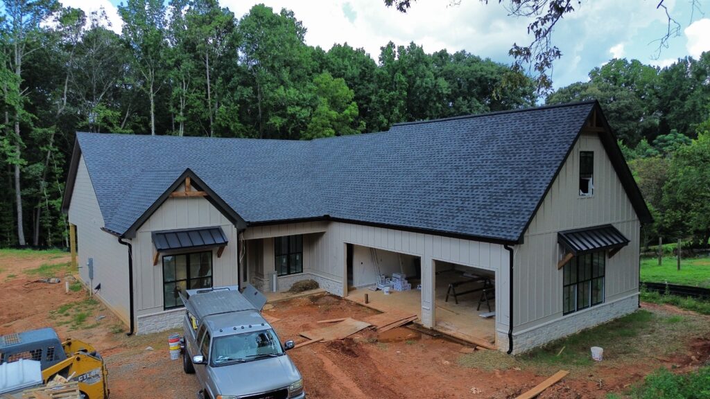New construction board-and-batten farmhouse with a newly installed architectural shingle roof